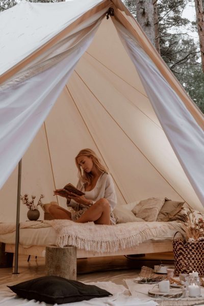 A woman is reading a book inside of glamping tent.
