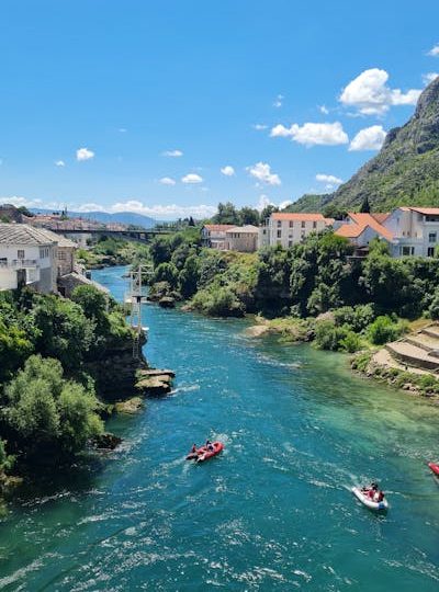 Pogled na reku neretvu sa Starog mosta u Mostaru. Dva camca plove duz reke Neretve.