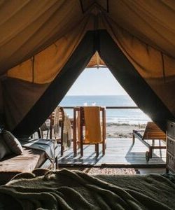 A glamping tent's interior in front of the beach.